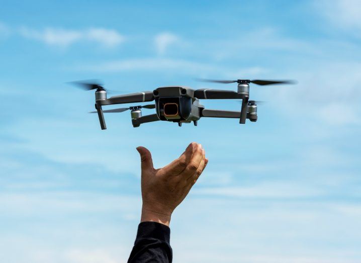 A hand reaching out to a drone flying above it. It is symbolic of the regulation that is allowing drones to take flight in Ireland and the rest of Europe.