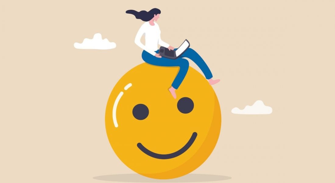 An illustration of a woman sitting on top of a giant smiley face while using her laptop.
