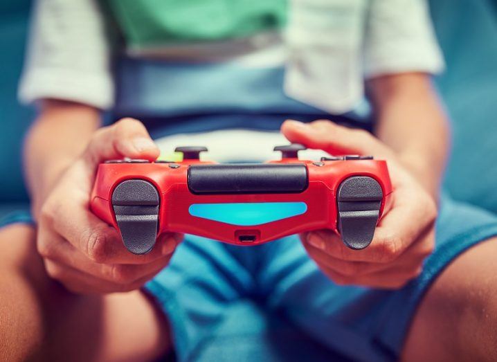 Child's hands holding a red PS4 controller.