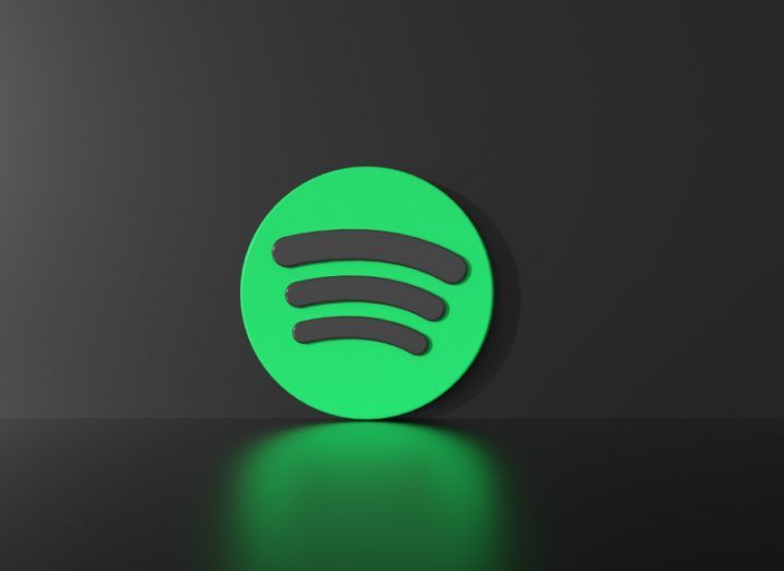 The Spotify logo on a black background, with the green 3D logo reflecting on a dark surface.