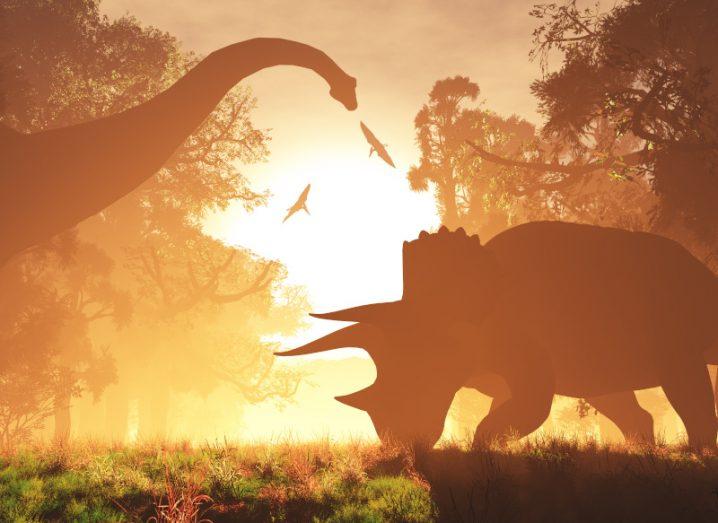 Two dinosaurs graze against a bright sunset.