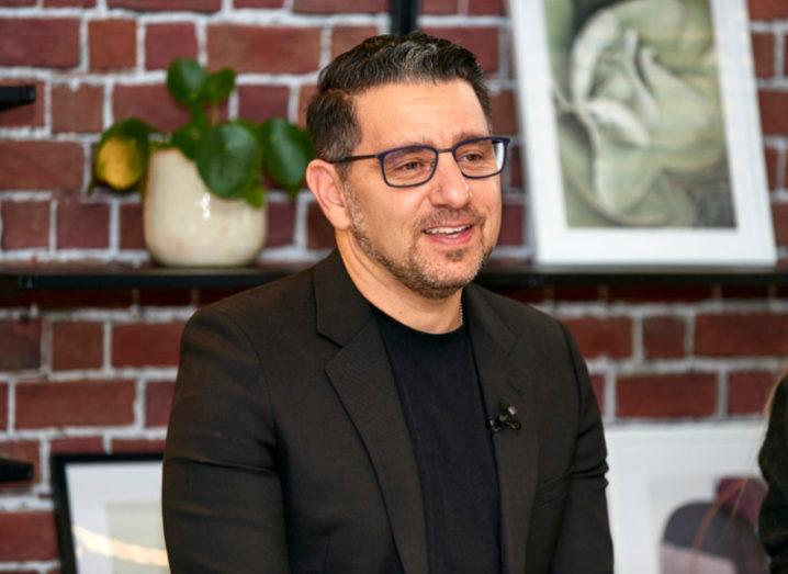 Photo of Panos Panay sitting in a dark suit in a casual office space.