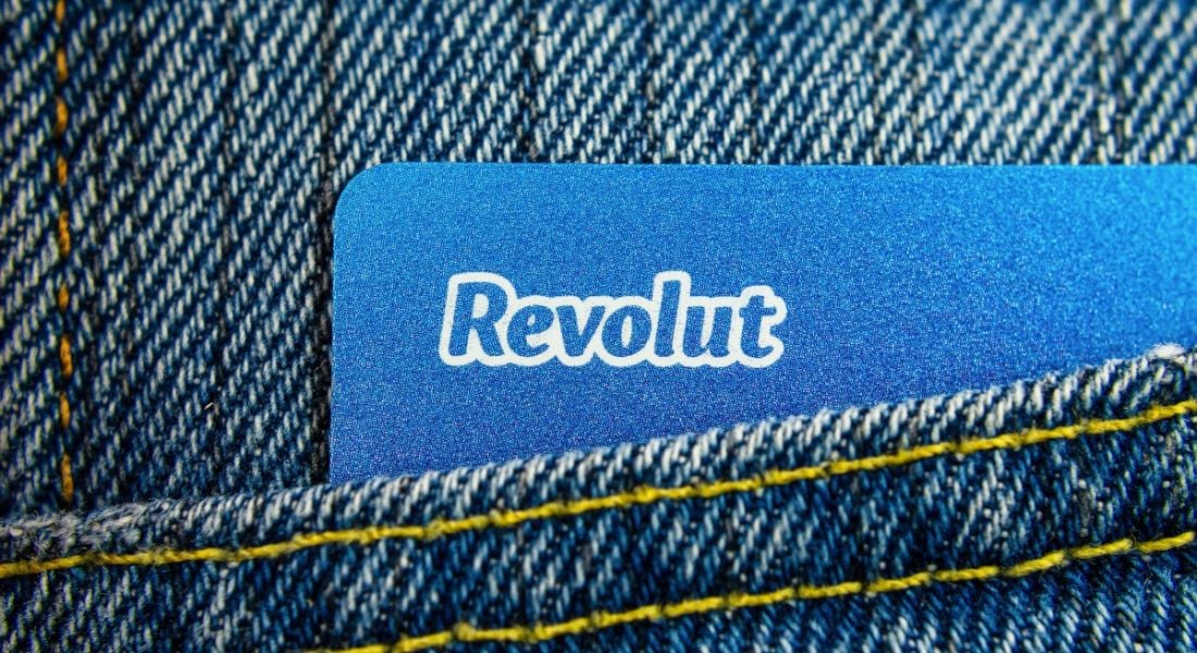 A close-up of a pocket on a pair of blue jeans with a blue Revolut card sticking out.